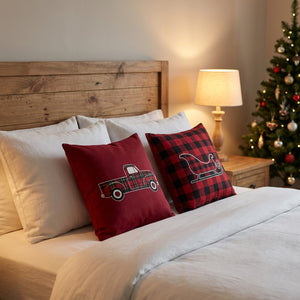 Housses de coussin de Noël sur un lit avec tête de lit en bois et lampe de chevet