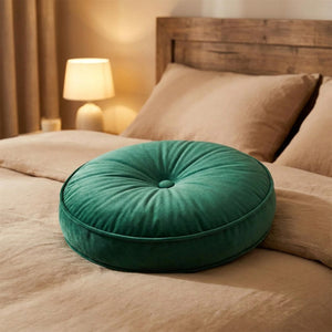 Coussin rond en velours vert émeraude sur un lit avec tête de lit en bois