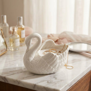 Vase cygne blanc utilisé comme vide-poche à bijoux sur une coiffeuse en marbre