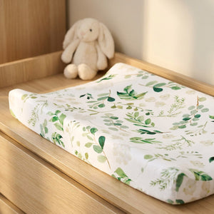 Housse de matelas à langer motif feuillage avec une peluche lapin dans une chambre lumineuse
