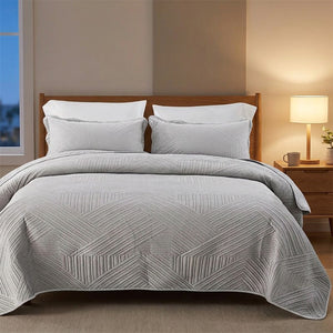 Couvre-lit matelassé en velours gris sur un lit dans une chambre moderne à la lumière tamisée