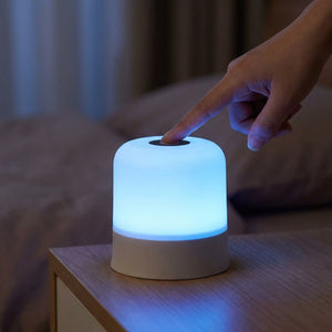 Main effleurant le bouton tactile de la lampe allumée en bleu