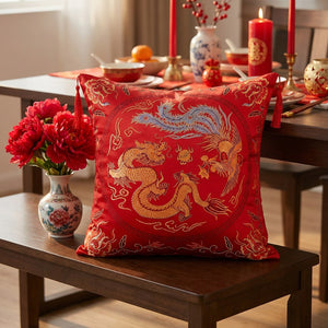 Housse de coussin brodée motif dragon et phénix posée sur un banc près d'une table dressée pour le nouvel an chinois