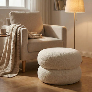 Pouf blanc utilisé comme repose-pieds devant un fauteuil en soirée