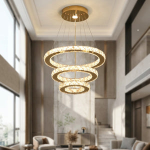 Lustre en cristal doré suspendu dans une entrée à haut plafond avec grande fenêtre