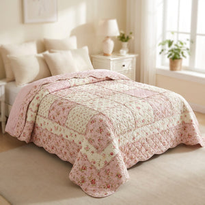 Couvre-lit rose matelassé sur un lit vu du pied avec coussins crème