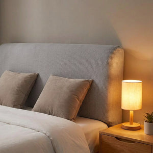 Housse de tête de lit gris clair dans une chambre chaleureuse éclairée par une lampe de chevet