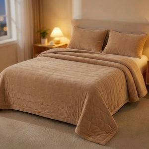 Couvre-lit matelassé beige sur un lit avec lampe de chevet allumée le soir