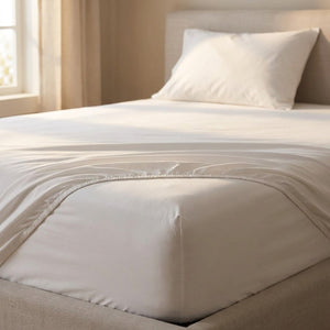 Drap-housse blanc installé sur un lit dans une chambre chaleureuse