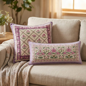 Housses de coussin ivoire et lilas à motif floral indien installées sur un canapé en lin beige avec un plaid