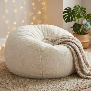 Pouf géant en fausse fourrure blanche dans une chambre d ado avec guirlande lumineuse