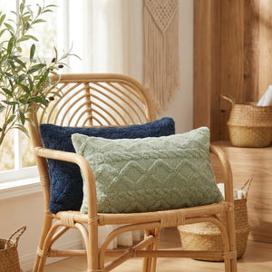 Housse de coussin lombaire en peluche sur un fauteuil en rotin près d'une fenêtre avec une plante verte