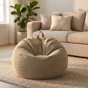 Pouf poire beige en velours côtelé utilisé comme siège devant un canapé en lin