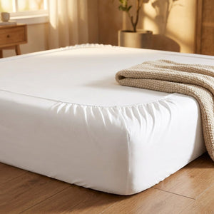 Drap-housse blanc épousant un matelas épais dans une chambre lumineuse