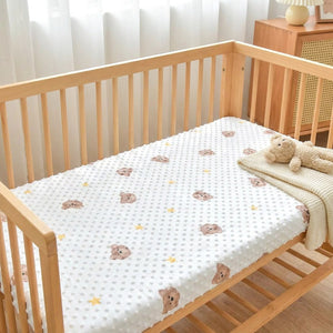 Drap-housse bébé installé sur un matelas de berceau dans une chambre chaleureuse