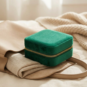 Boîte à bijoux en velours vert émeraude glissée dans un sac pour partir en voyage
