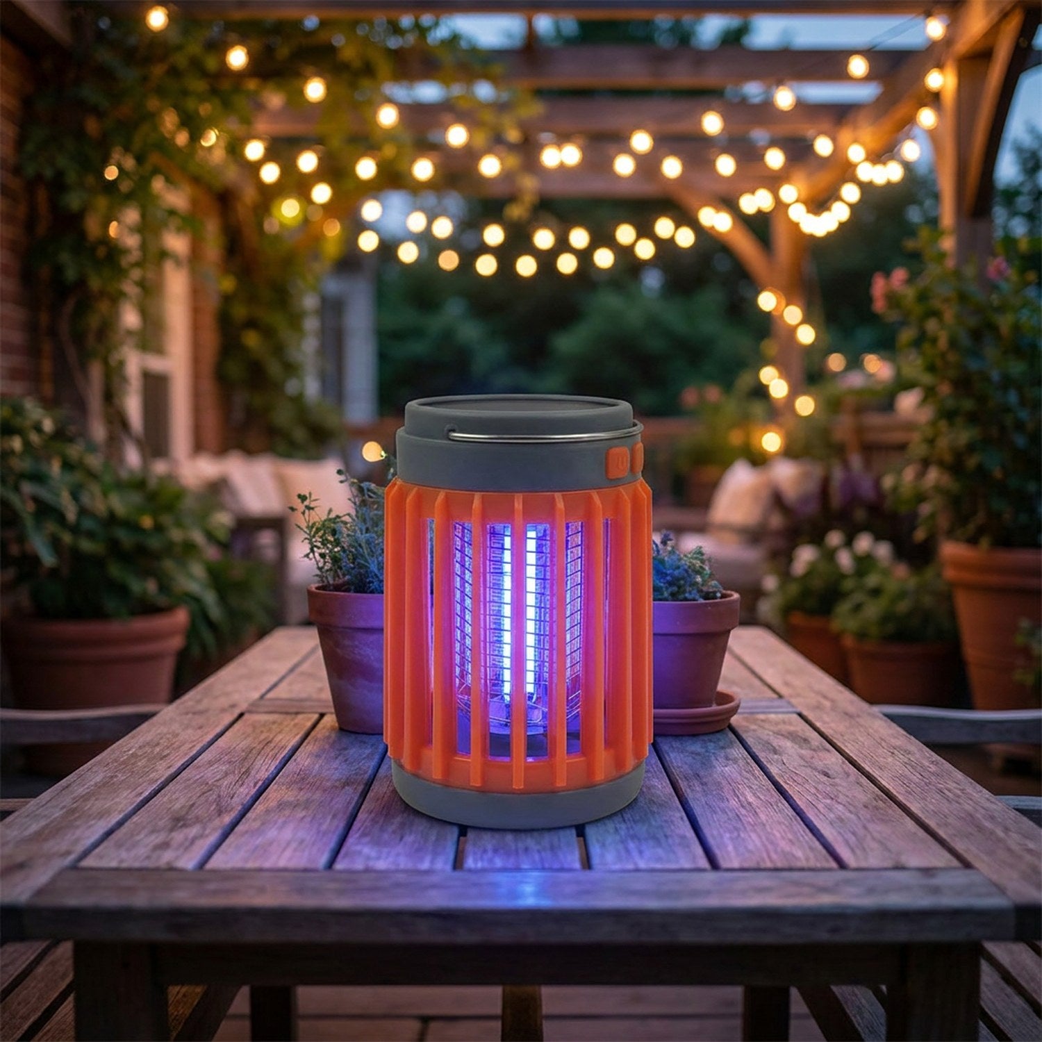 Lampe anti-moustiques UV orange sur table terrasse le soir avec guirlandes lumineuses