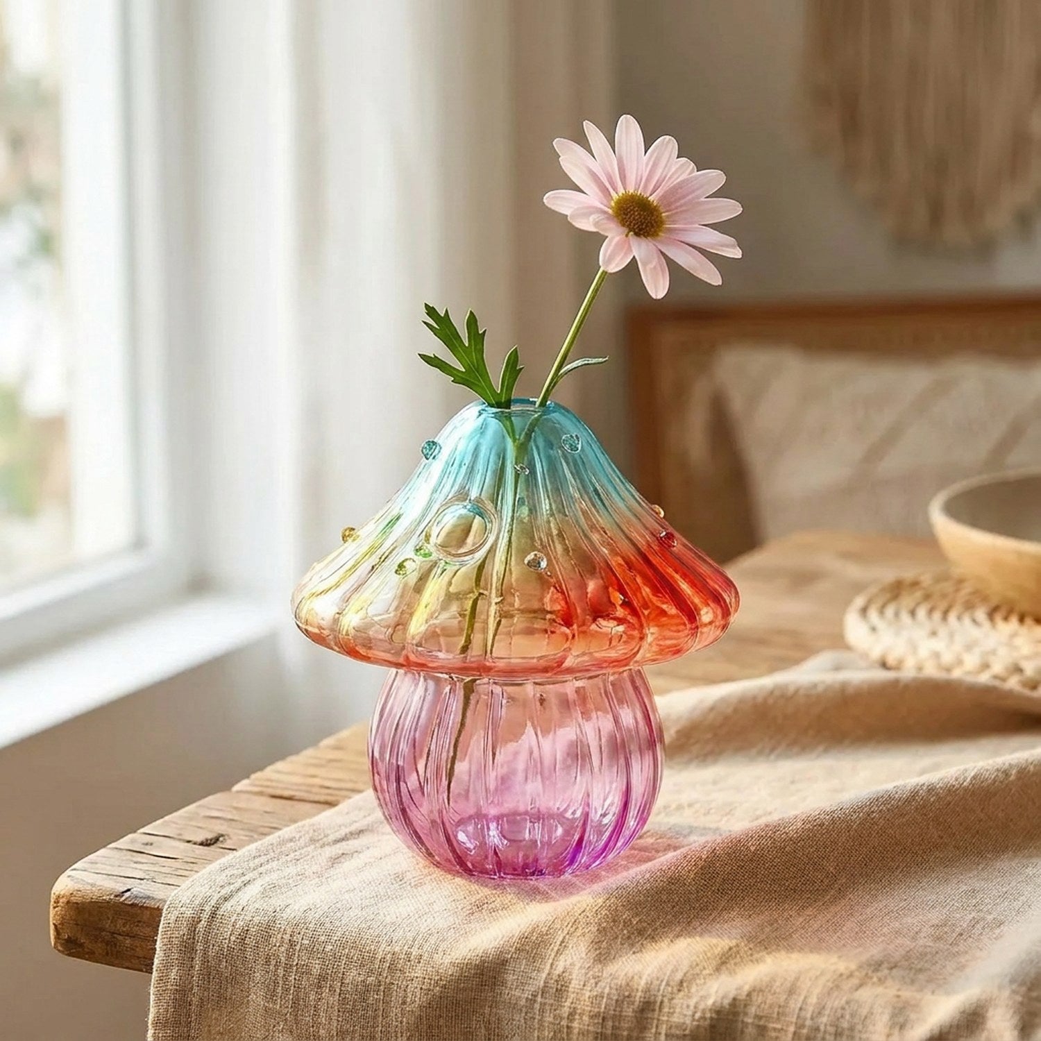 Vase champignon boho en verre sur table en bois avec marguerite rose
