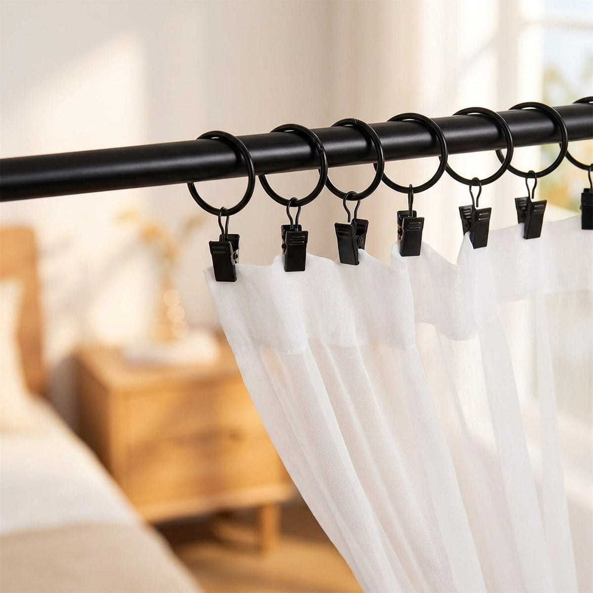 Anneaux de rideau noirs ouvrants avec un voilage blanc dans une chambre lumineuse