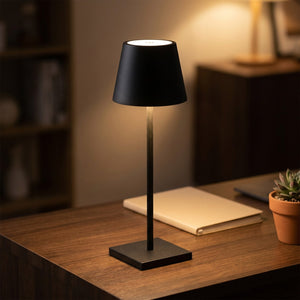 Lampe LED tactile noire allumée sur un bureau avec carnet et plante