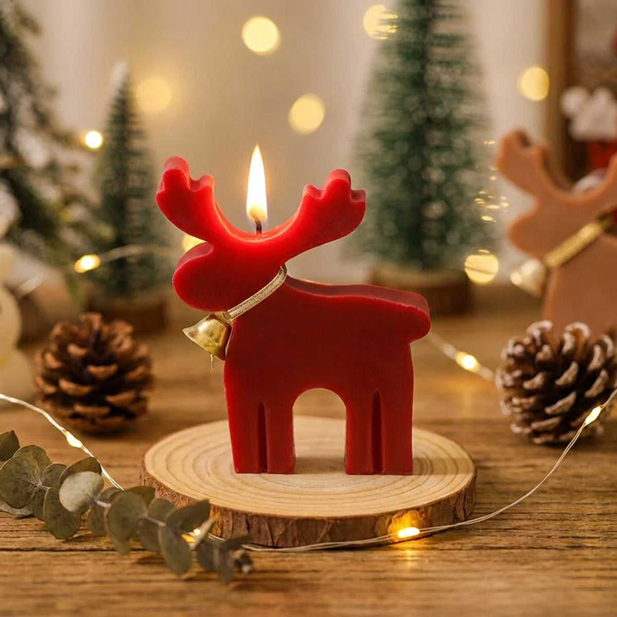 Bougie cerf rouge allumée sur table décorée pommes de pin et fairy lights