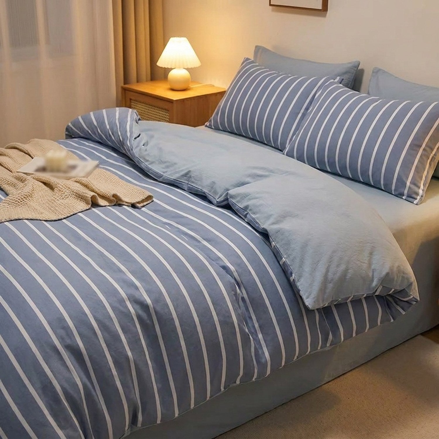 Housse de couette rayee bleue dans une chambre moderne eclairee par une lampe de chevet
