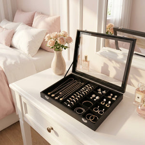 Boîte à bijoux noire ouverte sur coiffeuse avec bijoux organisés