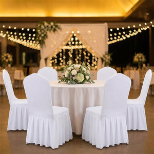 Rangée de chaises habillées de housses blanches autour d'une table ronde décorée pour un mariage