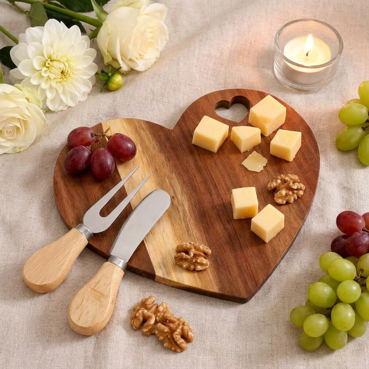 Planche apéritif cœur en bois avec fromages raisins et bougie sur nappe en lin