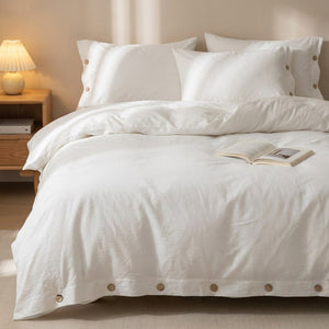 Housse de couette blanche posée sur un lit avec lampe de chevet en bois