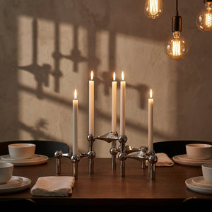 Bougeoir design moléculaire doré sur une table de salle à manger en bois sombre avec bougies allumées