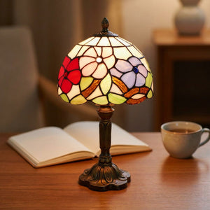Lampe style Tiffany allumée sur un bureau avec un livre ouvert et une tasse de thé