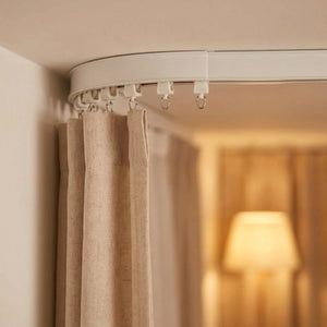 Rail de rideau plafond formant un angle avec rideau beige suspendu
