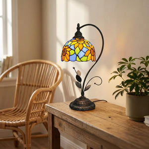 Lampe de table style Tiffany allumée dans un salon bohème avec fauteuil en rotin