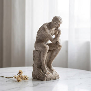 Statue de penseur en résine beige sur surface marbre blanc près fenêtre avec voilage