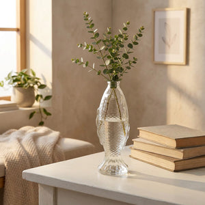 Vase bouteille poisson en verre avec eucalyptus sur bureau bois blanc