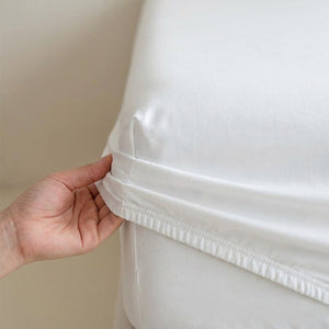 Détail de la bande élastique du drap housse tirée à la main sur le coin du matelas