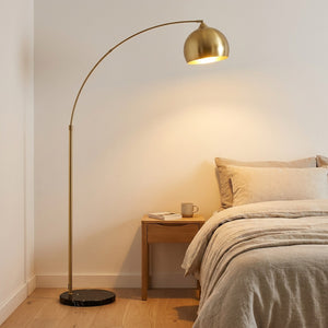 Lampadaire arc doré dans chambre scandinave avec literie lin