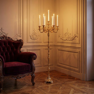 Chandelier doré 7 bras dans un coin de salon français avec fauteuil velours bordeaux
