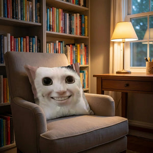 Coussin décoratif chat aux grands yeux sur un lit avec couverture blanche