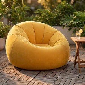 Pouf gonflable jaune posé sur une terrasse en bois avec une petite table