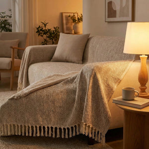 Housse de canapé beige drapée sur un canapé dans une ambiance chaleureuse avec lampe allumée