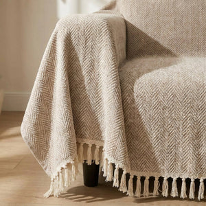 Gros plan sur la texture chevron en chenille et les franges à pompons de la housse beige