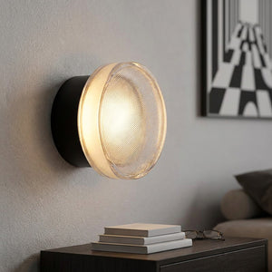 Applique murale LED noire au verre strié au dessus d'une table de chevet dans une chambre