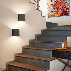 Applique murale LED noire installée dans une cage d'escalier avec lumière chaude diffusée haut et bas