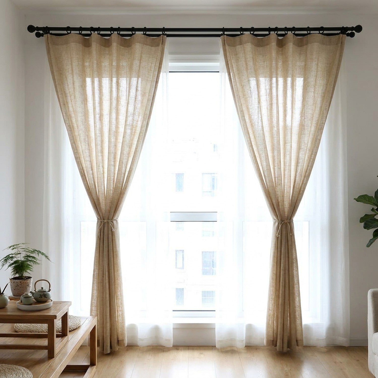 Salon lumineux avec rideaux en lin beige noués sur le côté d'une grande fenêtre