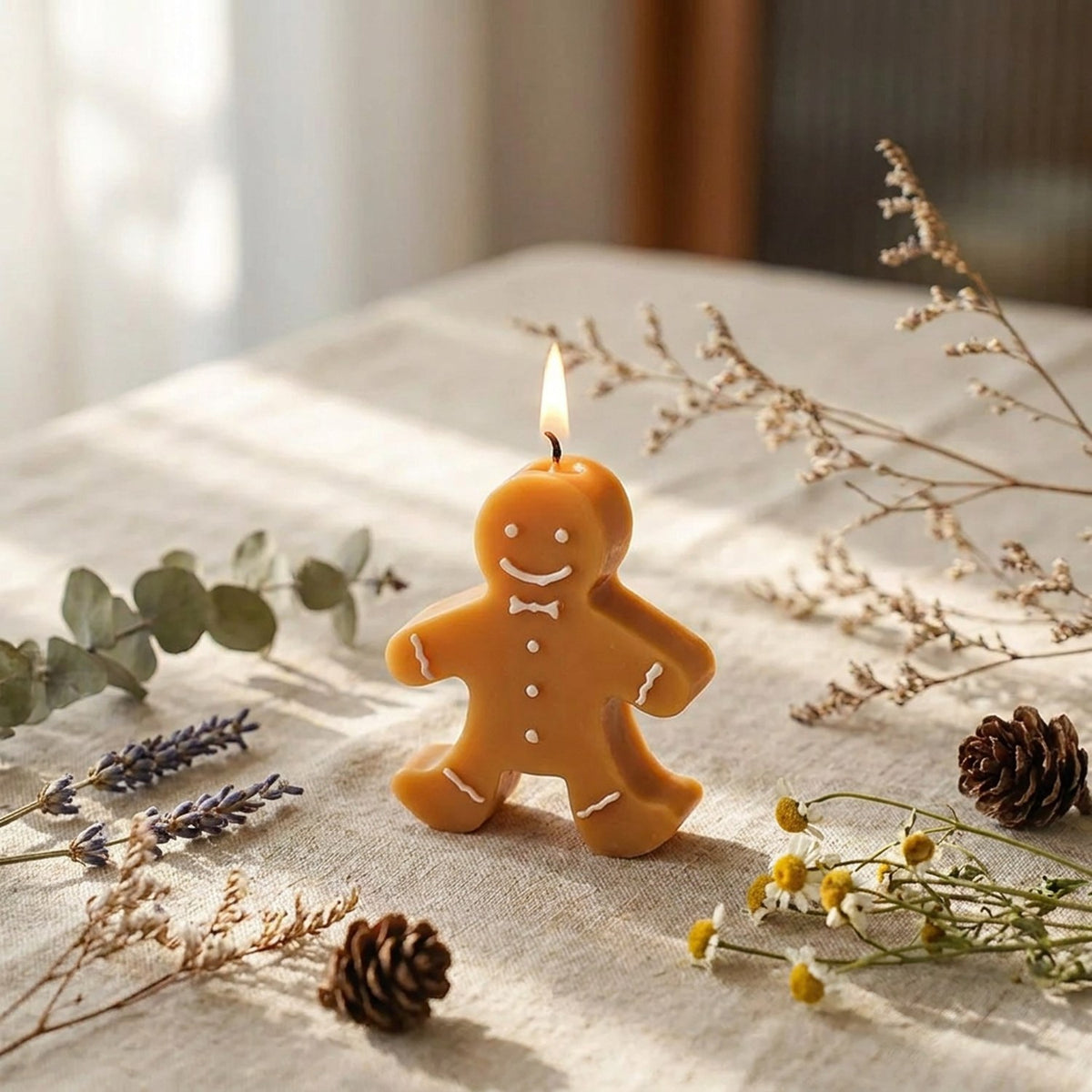 Bougie pain d'épice de Noël allumée sur nappe en lin avec fleurs séchées et eucalyptus
