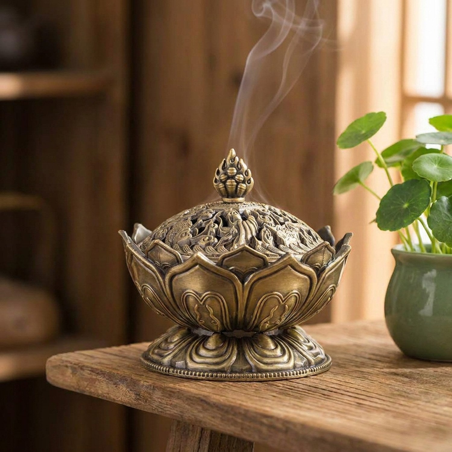 Porte-encens Bouddha bronze posé sur une étagère en bois avec plante verte et fumée d'encens