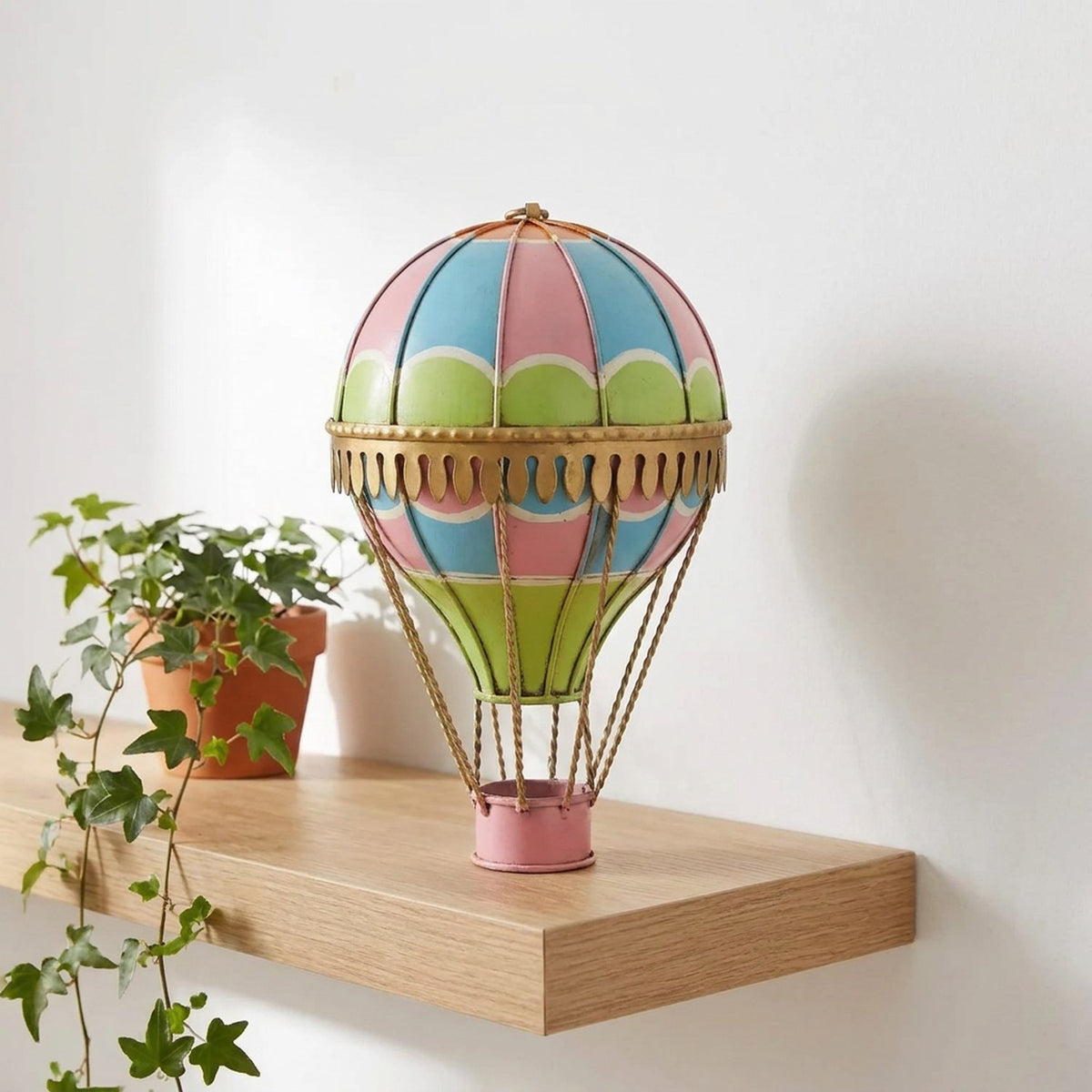 Ballon à air chaud décoratif en métal forgé posé sur une étagère en bois avec plante et livres dans un bureau