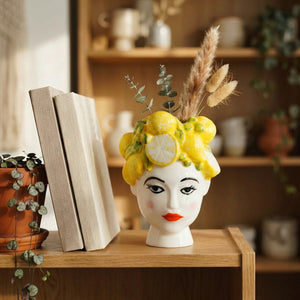Vase tête de femme céramique avec couronne de citrons sur une étagère en bois avec des branches séchées